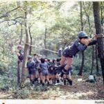 1976年　裏山での訓練　カブ隊による1本ロープ渡りの写真です。 最近はやっていない？ 1本ロープ渡りのコツは片足をロープに引っかけてもう一つの足をブランと下に落としてバランスを取る。できないスカウトもいましたね。 市之瀬パパ隊長が隊長を始めたころ。 ここは通称シカ広場？本当に木々が細い。 この1976年4月に日野2団から分かれた日野5団が生まれています。 スカウトの人数が爆発的に増えた時期です。 そう、正式にシニア隊が同じ4月に発足。